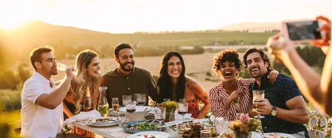 A group of people taking a photograph at an outdoor table.