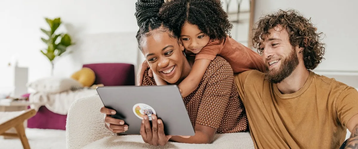 A family smiling together while looking at a tablet.