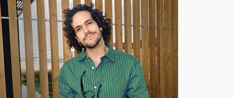 A person in a green shirt sitting beside a wooden screen.